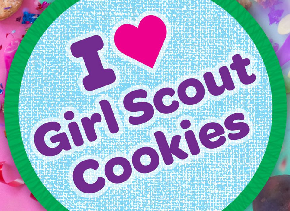 Graphic that shows a badge design that with “I heart Girl Scout Cookies”. The deign is multi colored with abstract background.